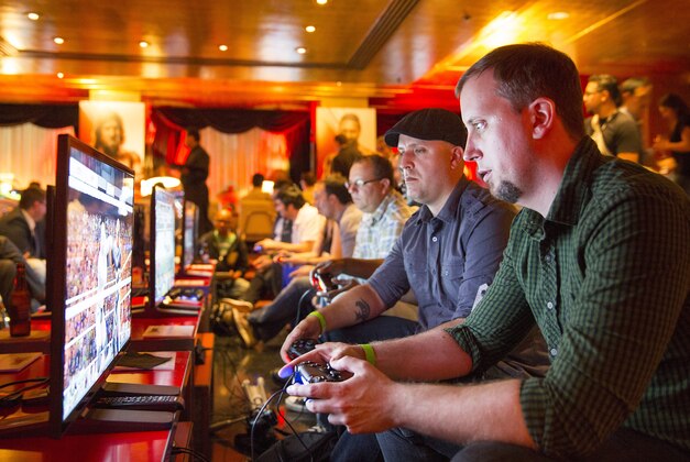 IMAGE DISTRIBUTED FOR 2K - Giant Bomb's Alex Navarro and GameSpot's Giancarlo Varanini play WWE 2K15 at the video game's press event at Cicada Restaurant, on Saturday, August 16, 2014 in Los Angeles. (Photo by Colin Young-Wolff/Invision for 2K/AP Images)
