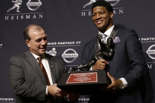 Florida State quarterback Jameis Winston, right, stands with FSU coach Jimbo Fisher while holding the Heisman Trophy after winning the award on Saturday, Dec. 14, 2013, in New York. (AP Photo/Julio Cortez)