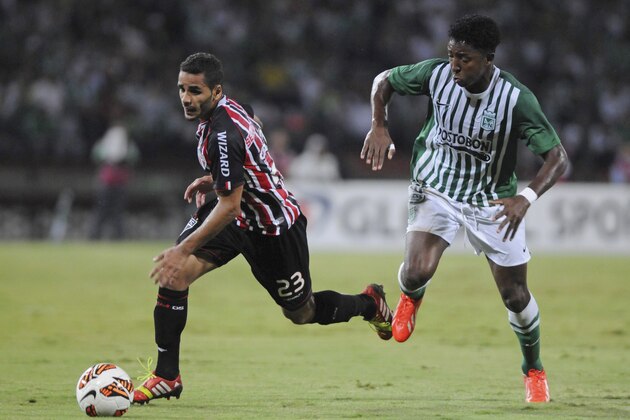 Douglas of Brazil's Sao Paulo, left, dribbles past Oscar Murillo of Colombia's Atletico Nacional at a Copa Sudamericana quarter final soccer match in Medellin, Colombia, Wednesday, Nov. 6, 2013. (AP Photo/Luis Benavides)