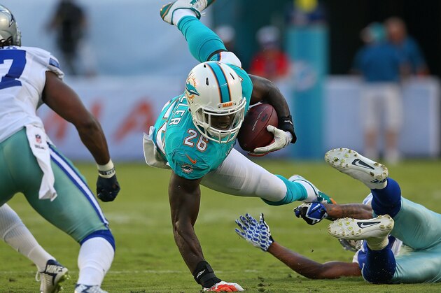 MIAMI GARDENS, FL - AUGUST 23: Lamar Miller #26 of the Miami Dolphins is tackled during a preseason game against the Dallas Cowboys at Sun Life Stadium on August 23, 2014 in Miami Gardens, Florida.  (Photo by Mike Ehrmann/Getty Images)