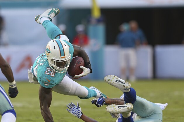 MIAMI GARDENS, FL - AUGUST 23:  Lamar Miller #26 of the Miami Dolphins is upended by Orlando Scandrick #32 of the Dallas Cowboys in the first quarter during a preseason game at Sun Life Stadium on August 23, 2014 in Miami Gardens, Florida.  (Photo by Mike Ehrmann/Getty Images)