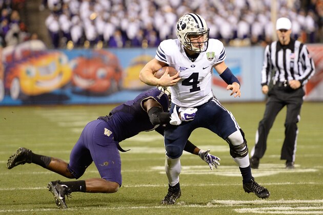 SAN FRANCISCO, CA - DECEMBER 27:  Taysom Hill #4 of the BYU Cougars runs with the ball, breaking the tackle of Sean Parker #1 of the Washington Huskies during the second quarter in the Fight Hunger Bowl at AT&T Park on December 27, 2013 in San Francisco, California.  (Photo by Thearon W. Henderson/Getty Images)