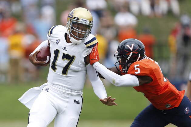 CHARLOTTESVILLE, VA - AUGUST 30: Brett Hundley #17 of the UCLA Bruins gets tackled by Tim Harris #5 of the Virginia Cavaliers during first half action at Scott Stadium on August 30, 2014 in Charlottesville, Virginia. (Photo by Joe Robbins/Getty Images)