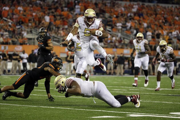 **RETRANSMISSION OF CBS118 FOR ALTERNATE CROP** Florida State quarterback Jameis Winston (5) leaps over guard Josue Matias, bottom, as Oklahoma State safety Jordan Sterns, left, is unable to stop Winston from reaching the end zone for a touchdown in the second half of an NCAA college football game, Saturday, Aug. 30, 2014, in Arlington, Texas. (AP Photo/Tony Gutierrez)