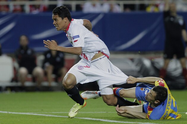 Sevilla's Carlos Bacca, left, and Valencia's Javi Fuego, right, fight for the ball during their Europa League semifinal first leg soccer match at the Ramon Sanchez Pizjuan stadium, in Seville, Spain on Thursday, April 24, 2014. (AP Photo/Miguel Angel Morenatti)