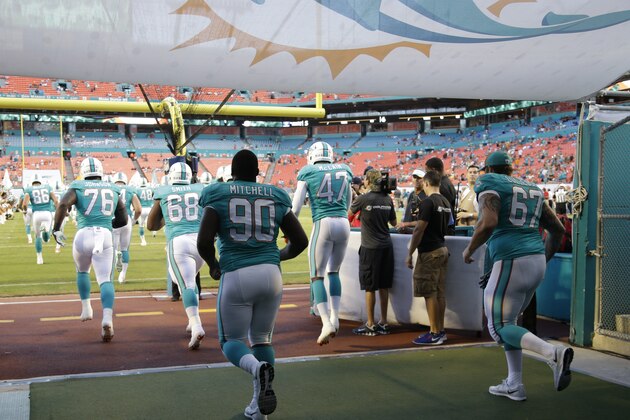 Miami Dolphins nose tackle Earl Mitchell (90) and Miami Dolphins guard Daryn Colledge (67) enter the field during the first half of an NFL preseason football game against the St. Louis Rams, Thursday, Aug. 28, 2014 in Miami Gardens, Fla.  (AP Photo/Lynne Sladky)