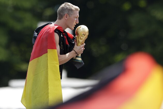 Bastian Schweinsteiger kisses the trophy during a fan party after the arrival of the German national soccer team in Berlin Tuesday, July 15, 2014. Germany beat Argentina 1-0 on Sunday to win its fourth World Cup title.  (AP Photo/Petr David Josek)