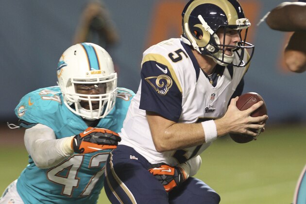 MIAMI GARDENS, FL - AUGUST 28:  Quarterback Garrett Gilbert #5 of the St. Louis Rams tries to evade Chris McCain #47 of the Miami Dolphins in the fourth quarter at Sun Life Stadium on August 28, 2014 in Miami Gardens, Florida.  (Photo by Marc Serota/Getty Images)