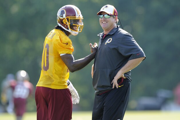 Washington Redskins quarterback Robert Griffin III, left, laughs with head coach Jay Gruden during an NFL football minicamp, Tuesday, June 17, 2014, in Ashburn, Va. (AP Photo/Nick Wass)