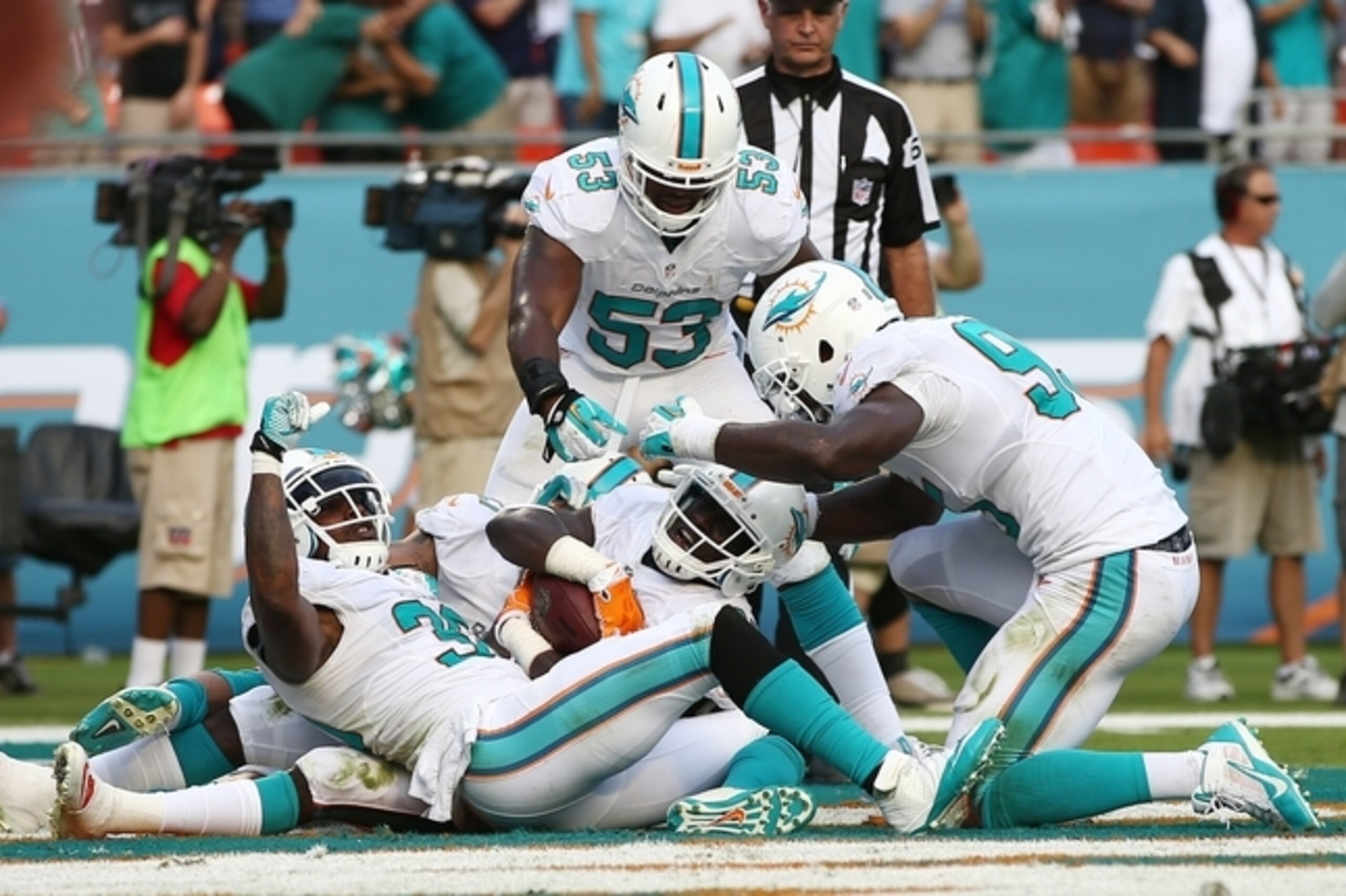Miami Dolphins Michael Thomas, center, is congratulated by teammates Chris Clemons (30), left, and Jelani Jenkins (53) after Thomas intercepted a pass intended for New England Patriots wide receiver Austin Collie (10) during the second half of an NFL football game, Sunday, Dec. 15, 2013, in Miami Gardens, Fla. The Dolphins defeated the Patriots 24-20. (AP Photo/J Pat Carter)