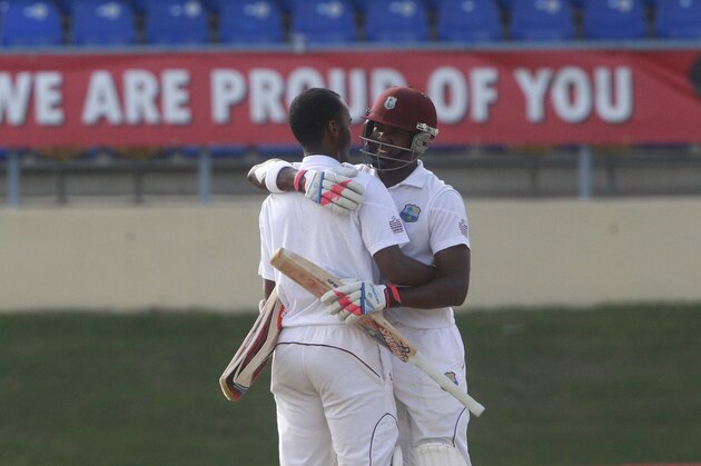 West Indies' batsman Kraigg Brathwaite, left, is hugged by his batting partner Darren Bravo, right, after scoring a half century during the second day of their second cricket Test match against New Zealand in Port of Spain, Trinidad, Tuesday, June 17, 2014. (AP Photo/Arnulfo Franco)