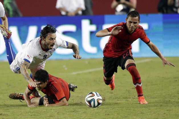 Chile's Mauricio Pinilla, top left, trips over Mexico's Miguel Herrera during the second half of an international friendly soccer match Saturday, Sept. 6, 2014, in Santa Clara, Calif. The game ended in a 0-0 draw. (AP Photo/Marcio Jose Sanchez)