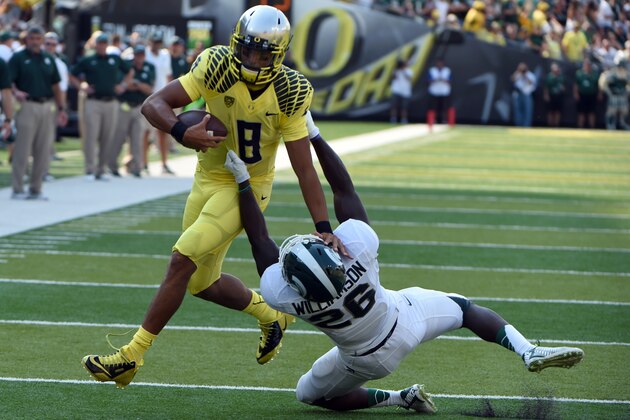 EUGENE, OR -SEPTEMBER 06; Quarterback Marcus Mariota #8 of the Oregon Ducks is brought down by safety RJ Williamson #26 of the Michigan State Spartans in the first quarter of the game at Autzen Stadium on September 6, 2014 in Eugene, Oregon. (Photo by Steve Dykes/Getty Images)