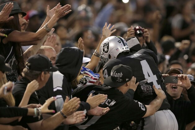 Oakland Raiders quarterback Derek Carr (4) celebrates with fans after a Raiders touchdown against the Seattle Seahawks during the first half of an NFL preseason football game in Oakland, Calif., Thursday, Aug. 28, 2014. (AP Photo/Marcio Jose Sanchez)