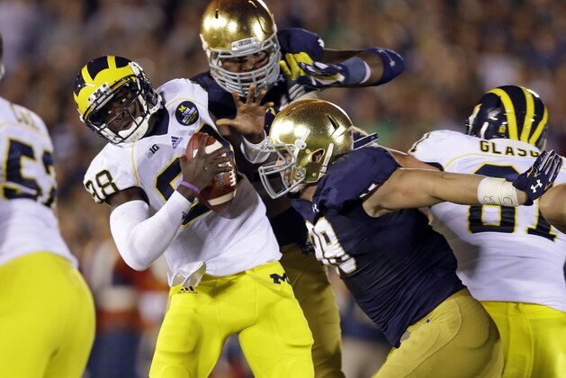 Michigan quarterback Devin Gardner, left, is pressured by Notre Dame defensive lineman Andrew Trumbetti, right, and Jarron Jones during the second half of an NCAA college football game in South Bend, Ind., Saturday, Sept. 6, 2014. (AP Photo/Michael Conroy)