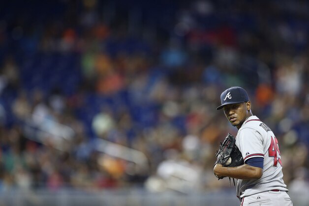 Atlanta Braves starter Julio Teheran watches Miami Marlins runner Donovan Solano at first base during the sixth inning of a baseball game in Miami, Sunday, Sept. 7, 2014.  The Marlins won 4-0.  (AP Photo/J Pat Carter)