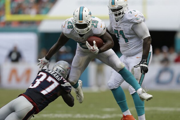 Miami Dolphins running back Knowshon Moreno (28) avoids a tackle by New England Patriots cornerback Alfonzo Dennard (37) during the second half of an NFL football game, in Miami Gardens, Fla., Sunday Sept. 7, 2014. (AP Photo/Wilfredo Lee)