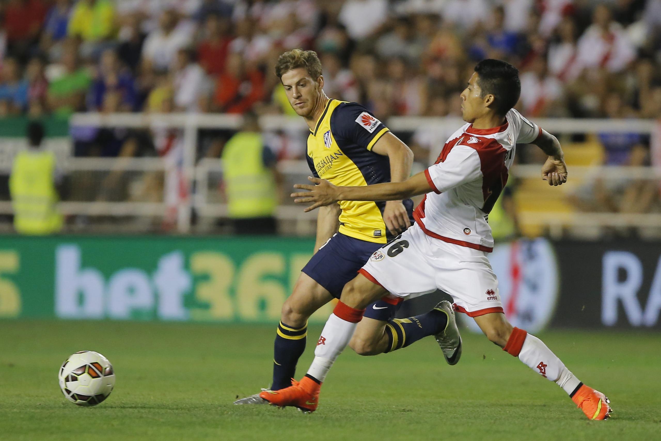 Rayo's Javier Aquino, right, vies for the ball with Atletico's Cristian Ansaldi, left, during a Spanish La Liga soccer match between Rayo Vallecano and Atletico Madrid at the Vallecas stadium in Madrid, Spain, Monday, Aug. 25, 2014. (AP Photo/Andres Kudacki)