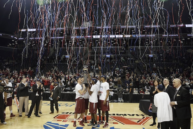 FILE - In this March 16, 2014, file photo, members of the Saint Joseph's team hold the championship trophy after an NCAA college basketball game against VCU in the championship round of the Atlantic 10 Conference tournament at the Barclays Center in New York. The Atlantic 10 was scheduled to play its tournament there through 2017, but will move in exchange for playing an ACC/A-10 doubleheader at Barclays during the 2015-16, 2016-17 and 2017-18 seasons. The A-10 tournament will then return to Barclays for three years starting in 2019. (AP Photo/Seth Wenig, File)