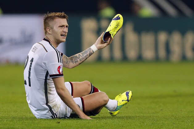 Germany’s Marco Reus shows his lost shoe during the Euro 2016 soccer qualifying group D match between Germany and Scotland in Dortmund, Germany, Sunday, Sept. 7, 2014. (AP Photo/Frank Augstein)