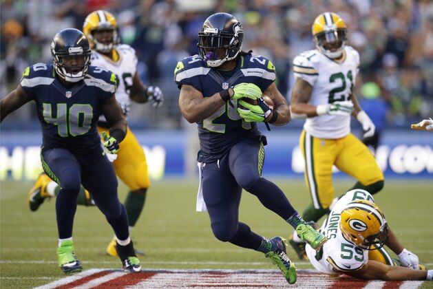 El running back Marshawn Lynch (24) de los Seahawks de Seattle acarrea el balón tras evadir a Brad Jones de los Packers de Green Bay el jueves 4 de septiembre de 2014. (AP Foto/Scott Eklund)