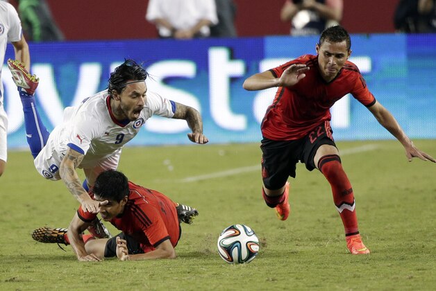 Chile's Mauricio Pinilla, top left, trips over Mexico's Miguel Herrera during the second half of an international friendly soccer match Saturday, Sept. 6, 2014, in Santa Clara, Calif. The game ended in a 0-0 draw. (AP Photo/Marcio Jose Sanchez)