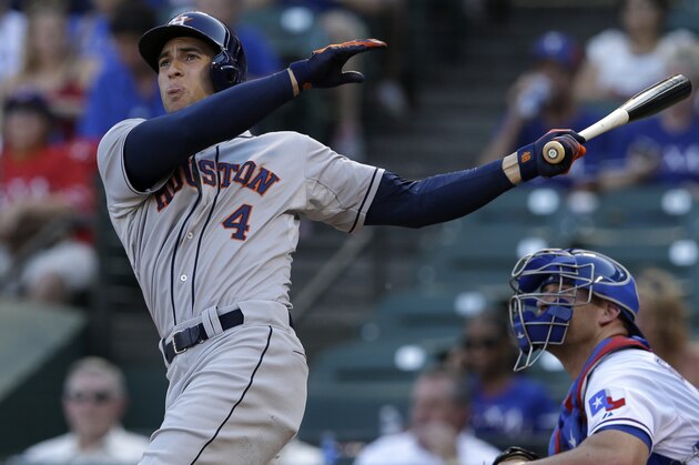 Houston Astros' George Springer follows through on a swing as Texas Rangers' Chris Gimenez watches in a baseball game, Tuesday, July 8, 2014, in Arlington, Texas. (AP Photo/Tony Gutierrez)