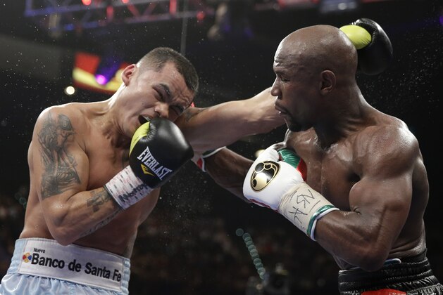 Marcos Maidana, left, from Argentina, trades blows with Floyd Mayweather Jr. in their WBC-WBA welterweight title boxing fight Saturday, May 3, 2014, in Las Vegas. Mayweather won the bout by majority decision. (AP Photo/Isaac Brekken)
