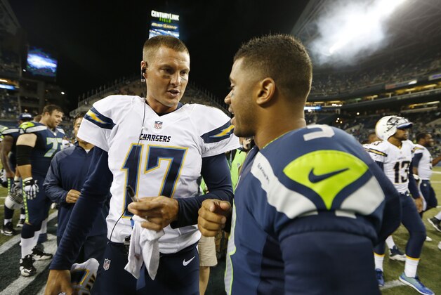Seattle Seahawks quarterback Russell Wilson and San Diego Chargers quarterback Philip Rivers (17) talk at the end of a preseason NFL football game, Friday, Aug. 15, 2014, in Seattle. (AP Photo/John Froschauer)