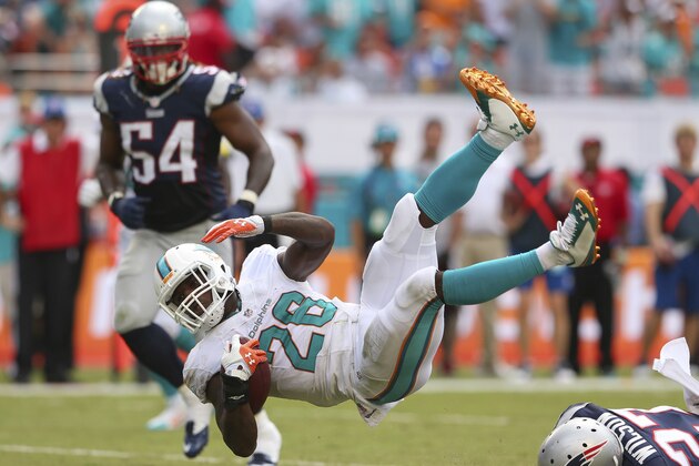 MIAMI GARDENS, FL - SEPTEMBER 07:   Lamar Miller #26 of the Miami Dolphins is brought down by Tavon Wilson #27 of the New England Patriots in the third quarter during a game  at Sun Life Stadium on September 7, 2014 in Miami Gardens, Florida.  (Photo by Mike Ehrmann/Getty Images)