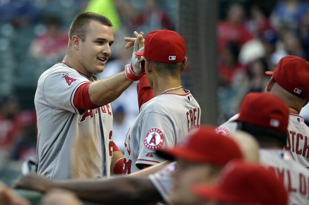 Los Angeles Angels' Mike Trout is congratulated in the dugout after scoring on a Albert Pujols triple in the first inning of a baseball game against the Texas Rangers, Wednesday, Sept. 10, 2014, in Arlington, Texas. (AP Photo/Tony Gutierrez)