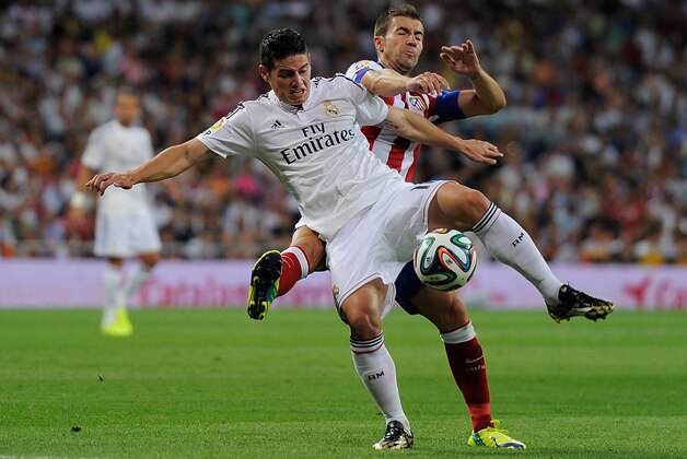 MADRID, SPAIN - AUGUST 19:  James Rodriguez is tackled by  Gabriel Fernandez alias 'Gabi' during the Supercopa first leg match between Real Madrid and Club Atletico de Madrid at Estadio Santiago Bernabeu on August 19, 2014 in Madrid, Spain.  (Photo by Denis Doyle/Getty Images)
