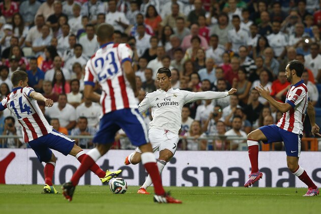 Real's Cristiano Ronaldo from Portugal kicks the ball in between players during a Spanish Supercup first leg soccer match between Real Madrid and Atletico Madrid at the Santiago Bernabeu stadium in Madrid, Spain, Tuesday, Aug. 19, 2014. (AP Photo/Andres Kudacki)