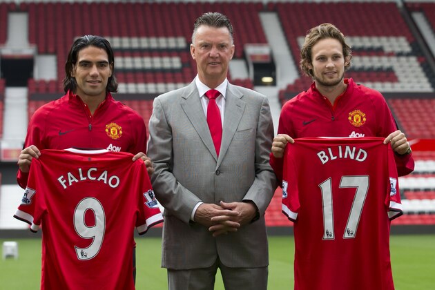 Manchester United's new players Radamel Falcao, left,  and Daley Blind, right, pose for photographs with manager Louis van Gaal at Old Trafford Stadium, Manchester, England, Thursday Sept. 11, 2014. The Colombian striker Falcao joined on a season-long loan deal from Ligue 1 side Monaco and Blind signed from Ajax as Louis van Gaal looks to bolster his attacking options. (AP Photo/Jon Super)