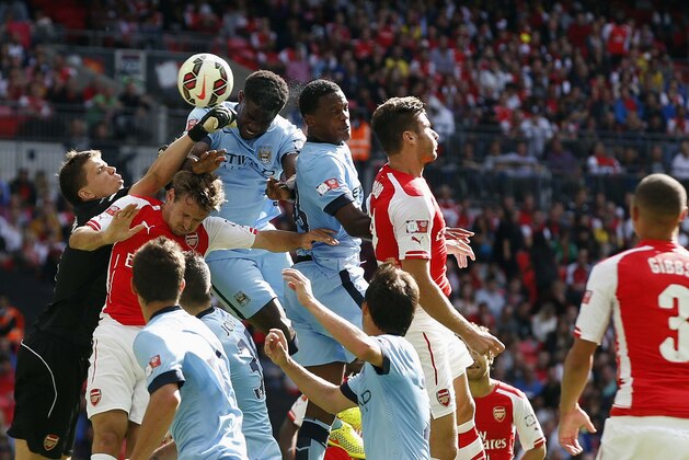 Arsenal's goalkeeper Wojciech Szczesny, left, punches the ball as Manchester City's Micah Richards, centre left,  heads the ball during the English FA Community Shield soccer match at Wembley Stadium, London Sunday, Aug. 10, 2014. (AP Photo/Alastair Grant)