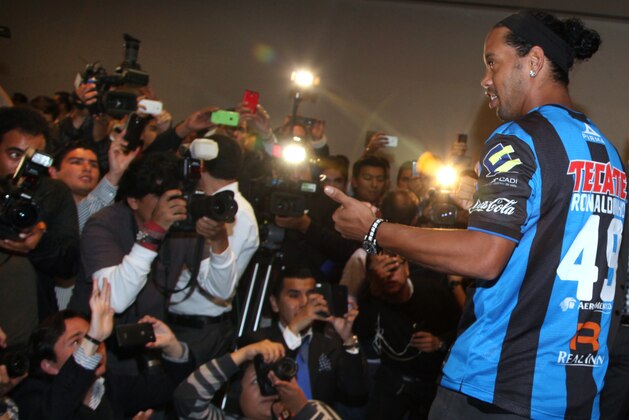 Brazil's Ronaldinho poses for a photo wearing his new Queretaro soccer club jersey at a press conference in Mexico City, Friday, Sept. 12, 2014. Mexican first-division club Queretaro signed the former 34-year-old soccer star, who had been without a club since leaving Brazil's Atletico Mineiro in July and had been negotiating with several clubs. The two-time FIFA world player of the year helped Atletico Mineiro win last year's Copa Libertadores for the first time. (AP Photo/Marco Ugarte)