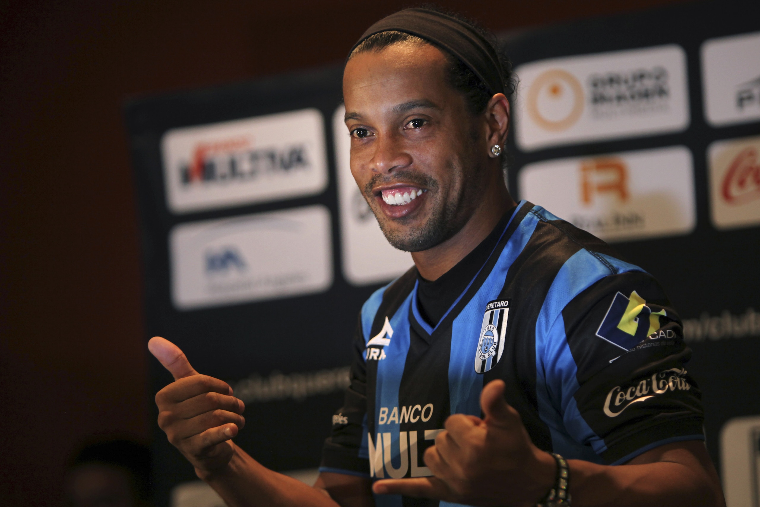 Brazil's Ronaldinho poses for a photo after slipping on his new Queretaro soccer club jersey at a press conference in Mexico City, Friday, Sept. 12, 2014. Mexican first-division club Queretaro signed the former 34-year-old soccer star, who had been without a club since leaving Brazil's Atletico Mineiro in July and had been negotiating with several clubs. The two-time FIFA world player of the year helped Atletico Mineiro win last year's Copa Libertadores for the first time. (AP Photo/Marco Ugarte)