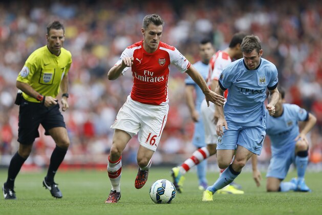 Arsenal's Aaron Ramsey, left, competes for the ball with Manchester City's James Milner during the English Premier League soccer match between Arsenal and Manchester City at Emirates Stadium in London, Saturday, Sept. 13, 2014. (AP Photo/Kirsty Wigglesworth)