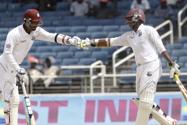 West Indies captain Denesh Ramdin, left, and batting partner Shivnarine Chanderpaul fist bump with gloved hands during the third day of their first cricket Test match against New Zealand in Kingston, Jamaica, Tuesday, June 10, 2014. (AP Photo/Arnulfo Franco)
