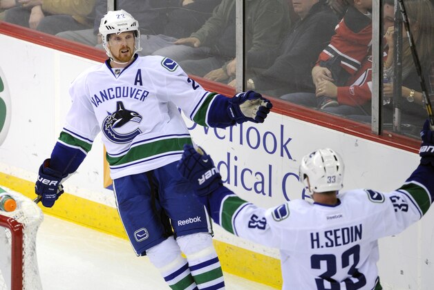 Vancouver Canucks' Daniel Sedin, left, of Sweden, celebrates his goal with brother Henrik Sedin (33) during the second period of an NHL hockey game against the New Jersey Devils, Thursday, Oct. 24, 2013, in Newark, N.J. (AP Photo/Bill Kostroun)