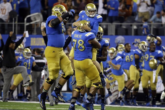 UCLA offensive linesman Alex Redmond (51) celebrates as Malcolm Bunche (78) lifts Jerry Neuheisel after their team scored a winning touchdown against Texas in the final minutes during the second half of an NCAA college football game, Saturday, Sept. 13,  2014, in Arlington, Texas. UCLA won 20-17. (AP Photo/Tony Gutierrez)