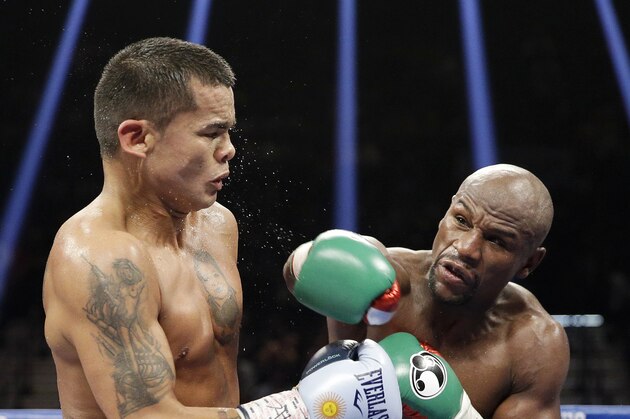 Floyd Mayweather, right, follows through on a punch at Marcos Maidana during their title boxing match Saturday, Sept. 13, 2014, in Las Vegas. (AP Photo/John Locher)