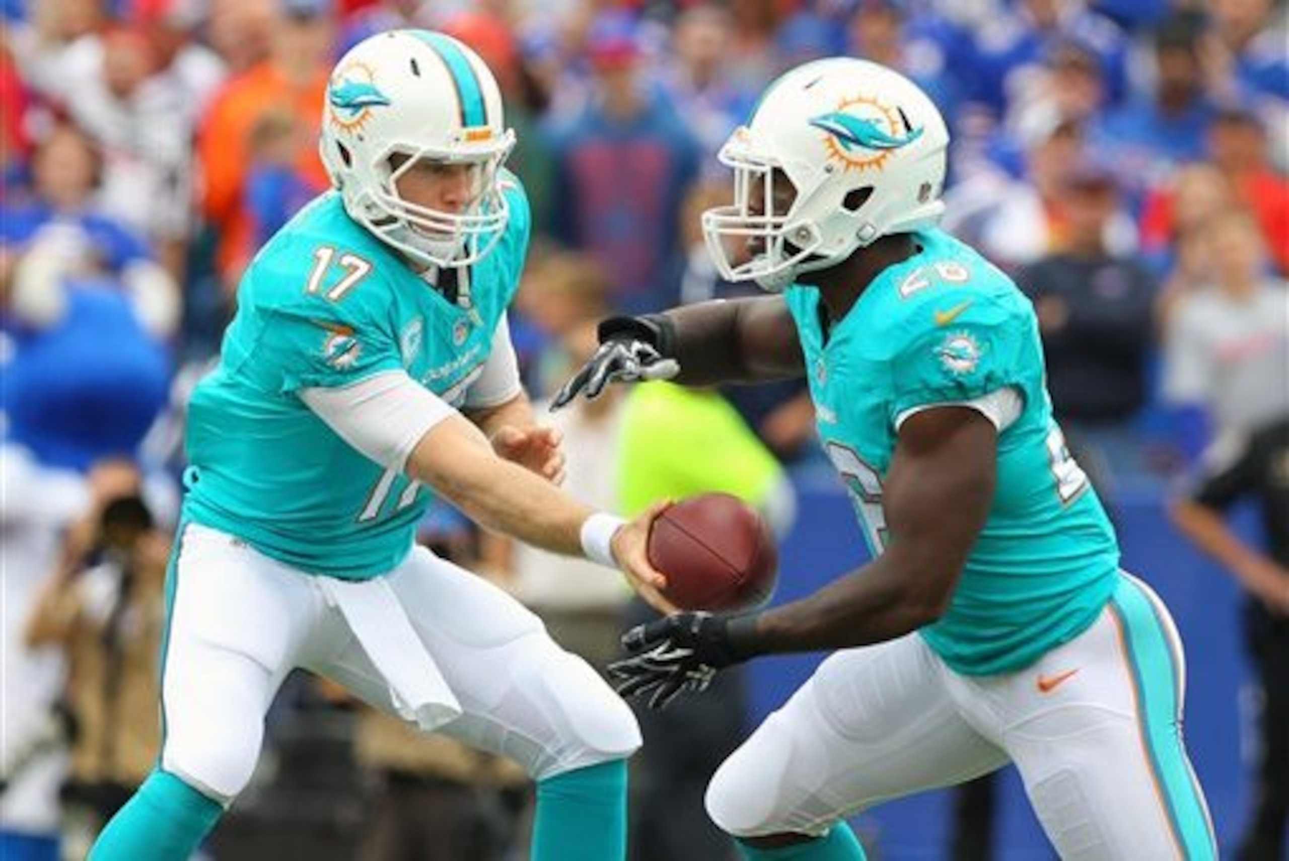 Miami Dolphins quarterback Ryan Tannehill (17) hands off to running back Lamar Miller (26) during the first half of an NFL football game on Sunday, Sept. 14, 2014, in Orchard Park, N.Y. (AP Photo/Bill Wippert)