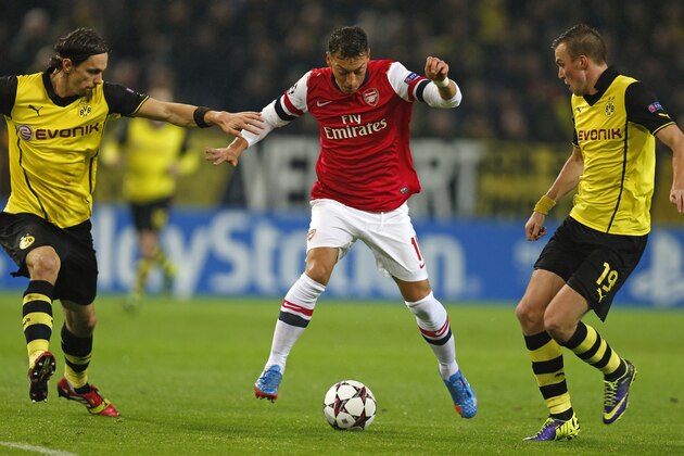Dortmund's Neven Subotic, left, and Dortmund's Kevin Grosskreutz, right, challenge Arsenal's Mesut Ozil during the Champions League group F soccer match between Borussia Dortmund and Arsenal FC in Dortmund, Germany, Wednesday,Nov.6,2013. (AP Photo/Frank Augstein)