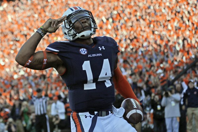 FILE - In this Nov. 30, 2013, file photo, Auburn quarterback Nick Marshall (14) salutes fans after scoring against Alabama on a 45-yard touchdown run during the first half of an NCAA college football game in Auburn, Ala. Marshall has made clutch plays and run No. 3 Tigers' offense with increasing proficiency in win after win. Now, his coaches touting him as Heisman worthy. (AP Photo/Dave Martin, File)