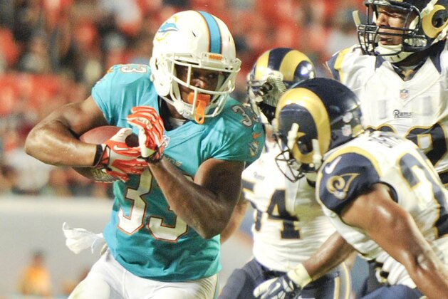 Aug 28, 2014; Miami Gardens, FL, USA; Miami Dolphins running back Daniel Thomas (33) runs the ball as St. Louis Rams safety Christian Bryant (26) looks to make the tackle  during the second quarter of the game  at Sun Life Stadium. Miami defeated the Rams 14-13.  Mandatory Credit: Brad Barr-USA TODAY Sports