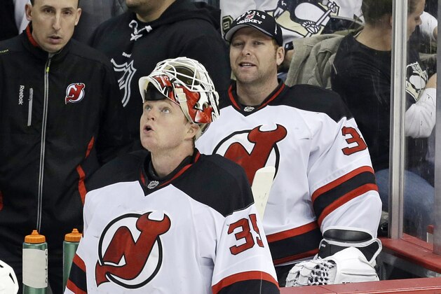 New Jersey Devils goalie Cory Schneider, left, looks at the scoreboard as he stands in front of New Jersey Devils goalie Martin Brodeur during a timeout in the first period of an NHL hockey game against the Pittsburgh Penguins in Pittsburgh, Friday, Dec. 13, 2013. (AP Photo/Gene J. Puskar)