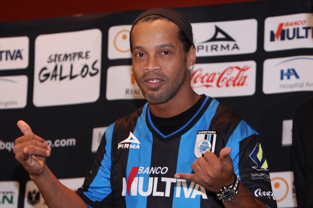 Brazil's Ronaldinho dons his new Queretaro soccer club jersey at a press conference in Mexico City, Friday, Sept. 12, 2014. Mexican first-division club Queretaro signed the former 34-year-old Brazil star, who had been without a club since leaving Brazil's Atletico Mineiro in July and had been negotiating with several clubs. The two-time FIFA world player of the year helped Atletico Mineiro win last year's Copa Libertadores for the first time. (AP Photo/Marco Ugarte)