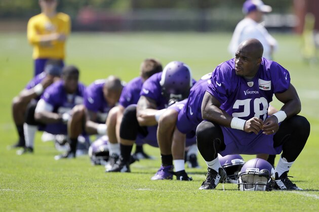 FILE - In this July 26, 2014, file photo,Minnesota Vikings running back Adrian Peterson, right, stretches during NFL football training camp in Mankato, Minn. After a day of public pressure from angry fans and concerned sponsors, the Vikings have reversed course and placed star  Peterson on the exempt-commissioner's permission list, the team announced Wednesday, Sept. 17, 2014. The move that will require him to stay away from the team while he addresses child abuse charges in Texas. (AP Photo/Charlie Neibergall, File)
