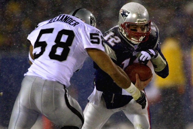 New England Patriots quarterback Tom Brady, right, covers the ball as he gets sacked by Oakland Raiders linebacker Elijah Alexander (58) during the second half of the the AFC Divisional Playoff game at Foxboro Stadium, in Foxboro, Mass., Saturday Jan. 19, 2002. (AP Photo/Charles Krupa)